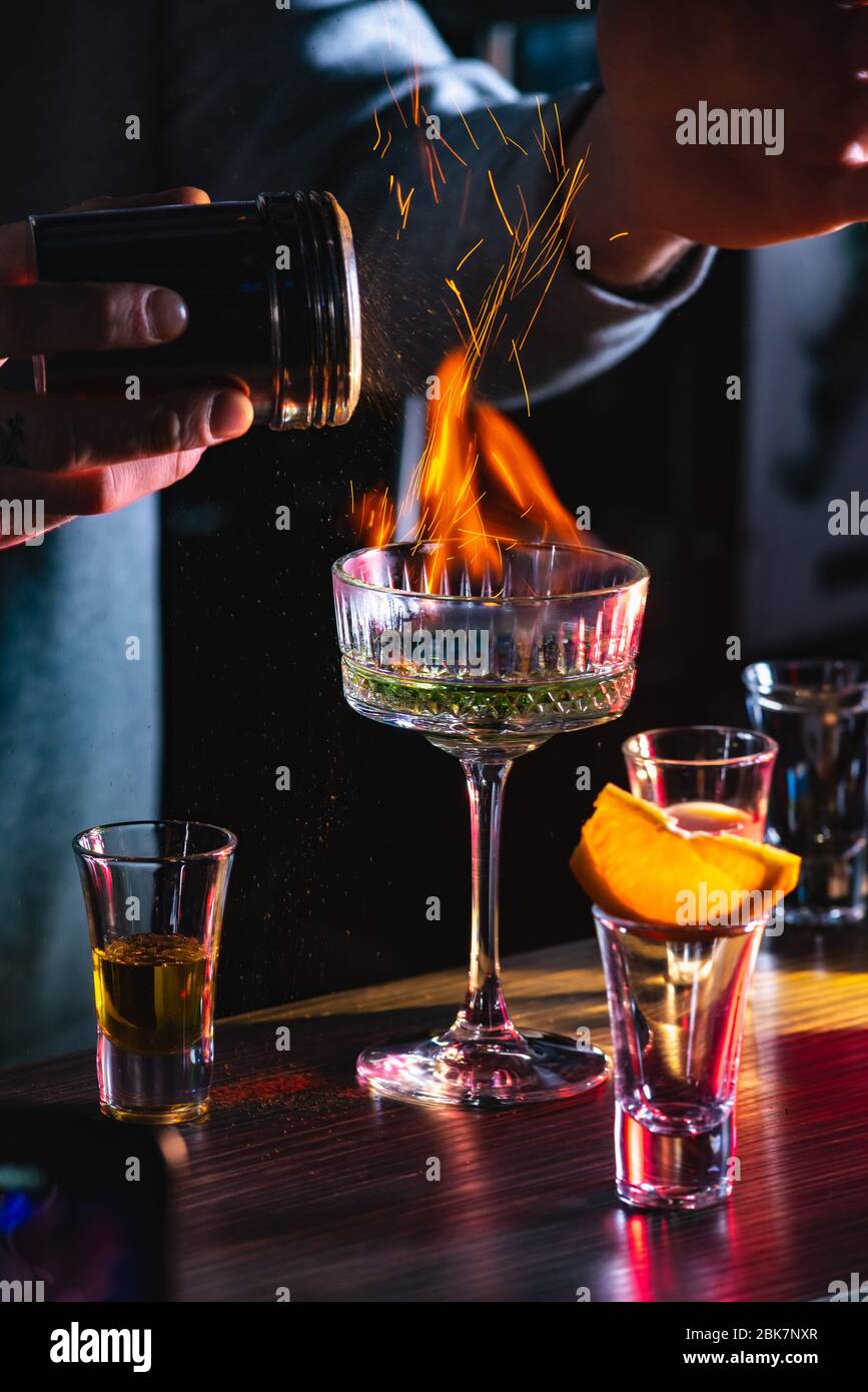 Male bartender holds fired up sugar above delicious alcohol cocktail Stock Photo