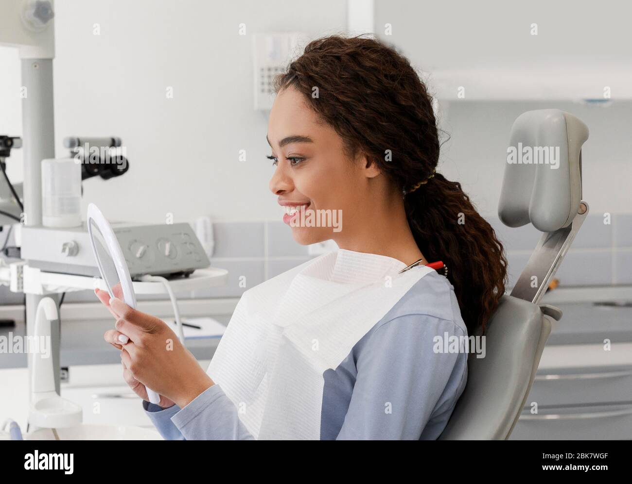 Beautiful black lady checking her white smile in mirror Stock Photo