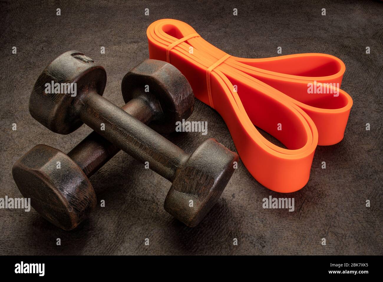 old rusty dumbbells and resistance bands on textured handmade bark paper, execise and fitness concept Stock Photo