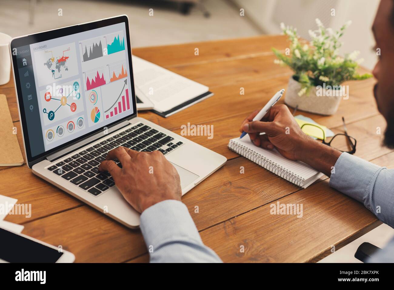 Black entrepreneur analyzing graph on laptop at workplace Stock Photo
