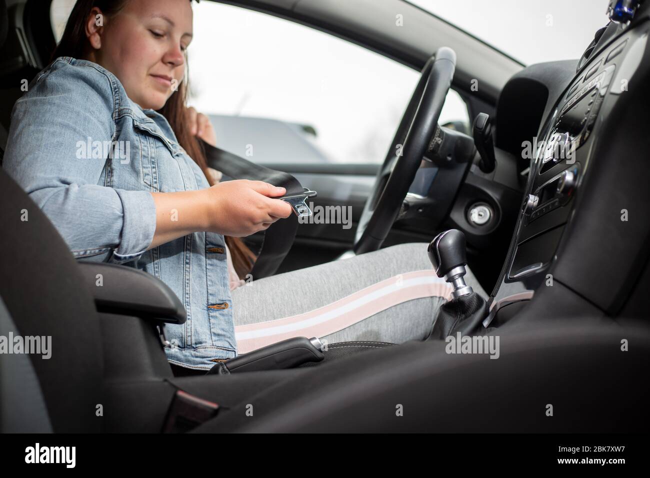 Driver woman fastening seat belt in the car, against car crash, safety concept, safe transport