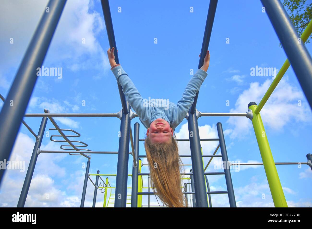 Little girl hanging upside down on parallel bars at playground Stock ...