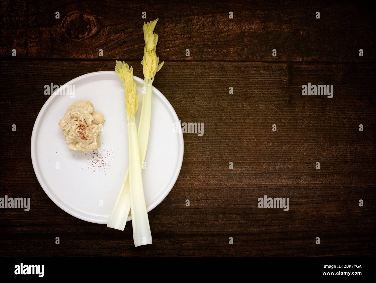 Fresh stick celery with hummus on wooden table Stock Photo