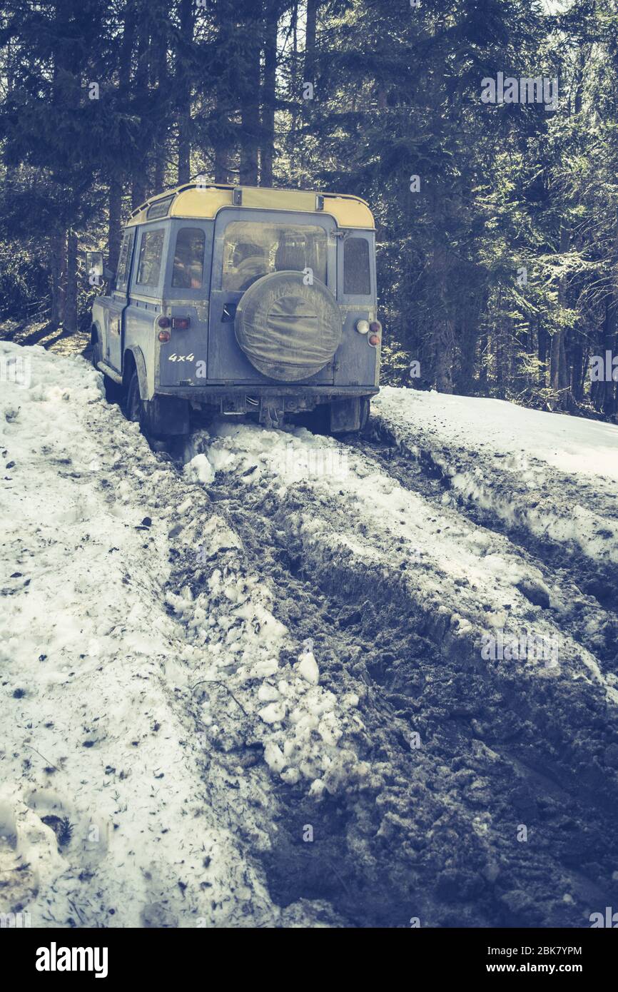 Blue SUV Sticks in Deep Snow Slips. Jeep Driving Along a Forest Road and Stuck in Pile of Mud and Snow. Stock Photo