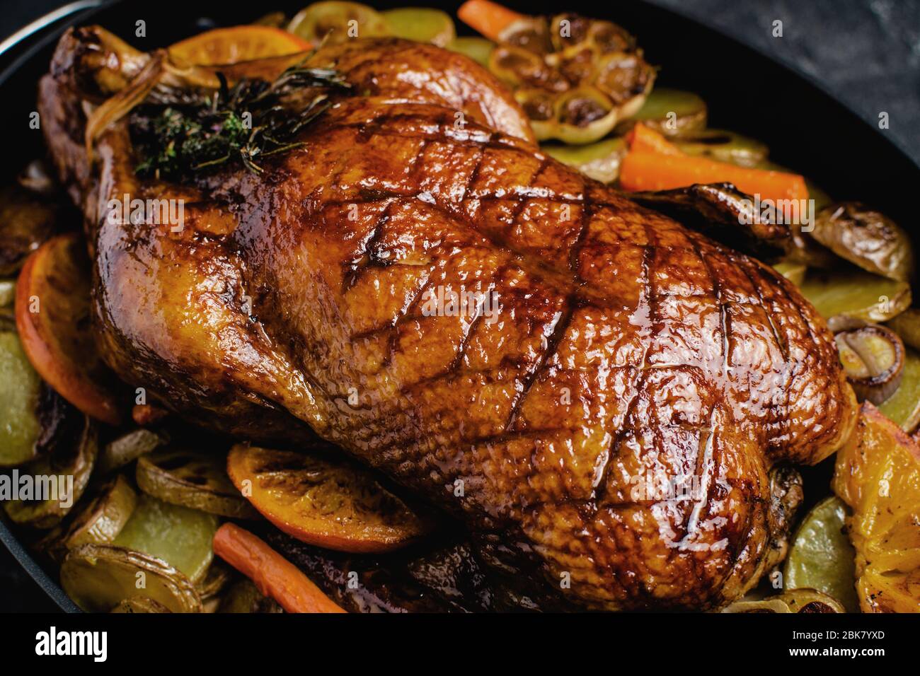 Whole Duck Roasted with Oranges, Carrots and Potatoes on Rustic Dark Stone Background Stock Photo