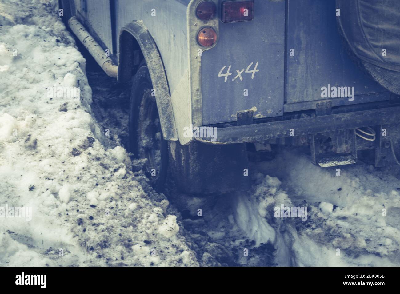 SUV Driving Along a Forest Road and Stuck in Pile of Mud and Snow. Blue Jeep Sticks in Deep Snow Slips. Stock Photo