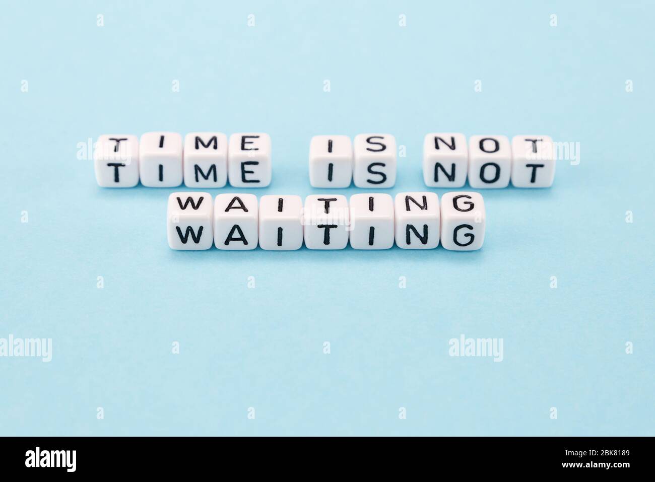 time is not waiting for you do it now - motivational phrase composed with cubes on blue background Stock Photo