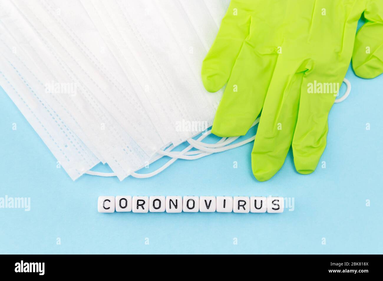 medical masks, gloves and coronovirus word composed with cubes on blue background Stock Photo