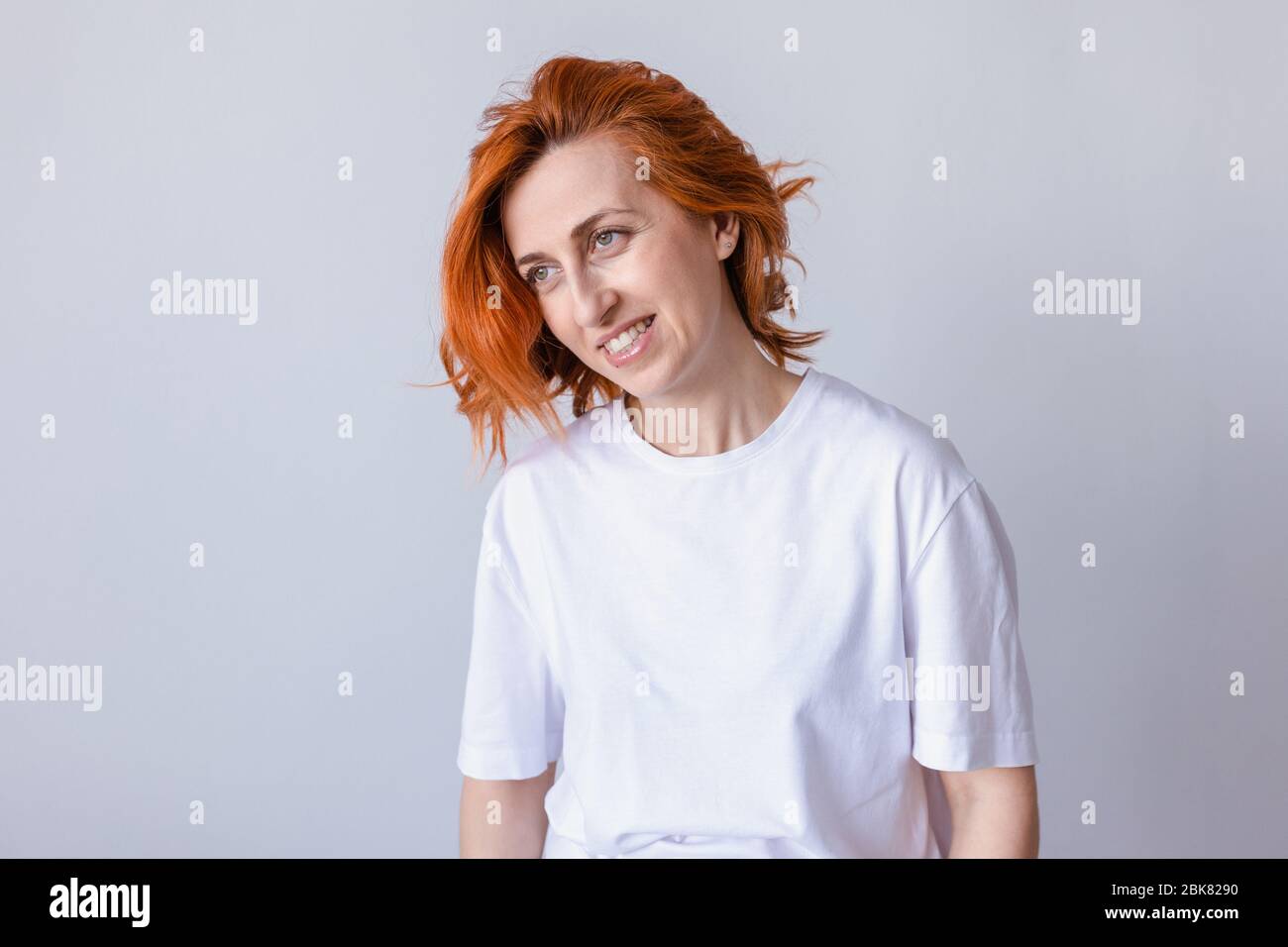 Smiling redhead woman looking somewhere wearing white t-shirt Stock Photo