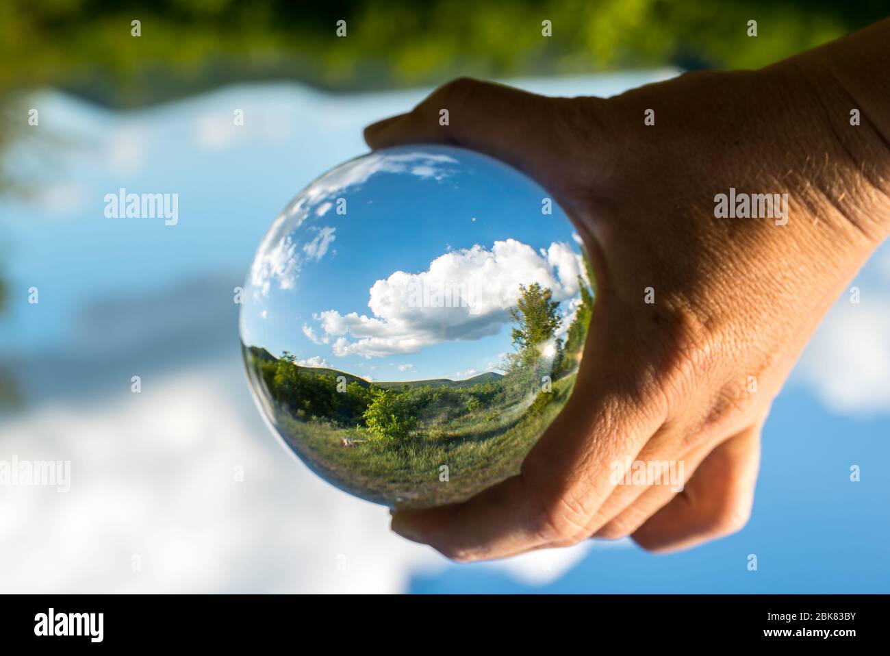 The future of the nature. Man holds in his hand a crystal sphere, inside with green trees and blue sky. Stock Photo