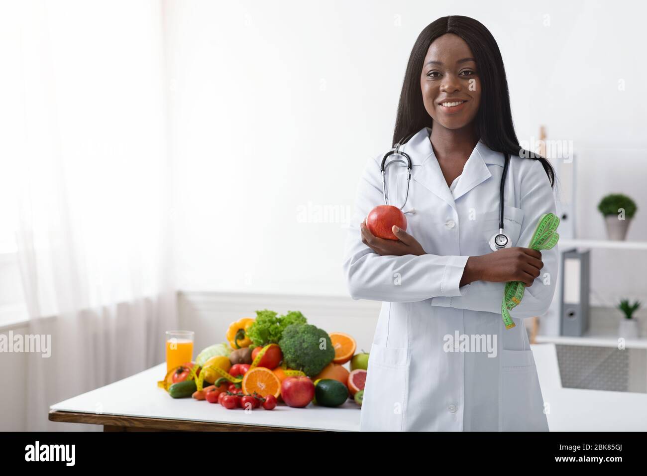 Friendly black woman dietician with apple and tape Stock Photo