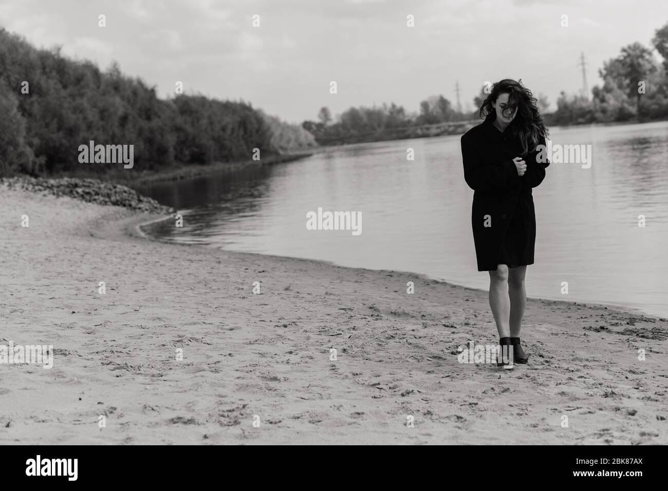 Woman in the coat walking along the river bank Stock Photo - Alamy