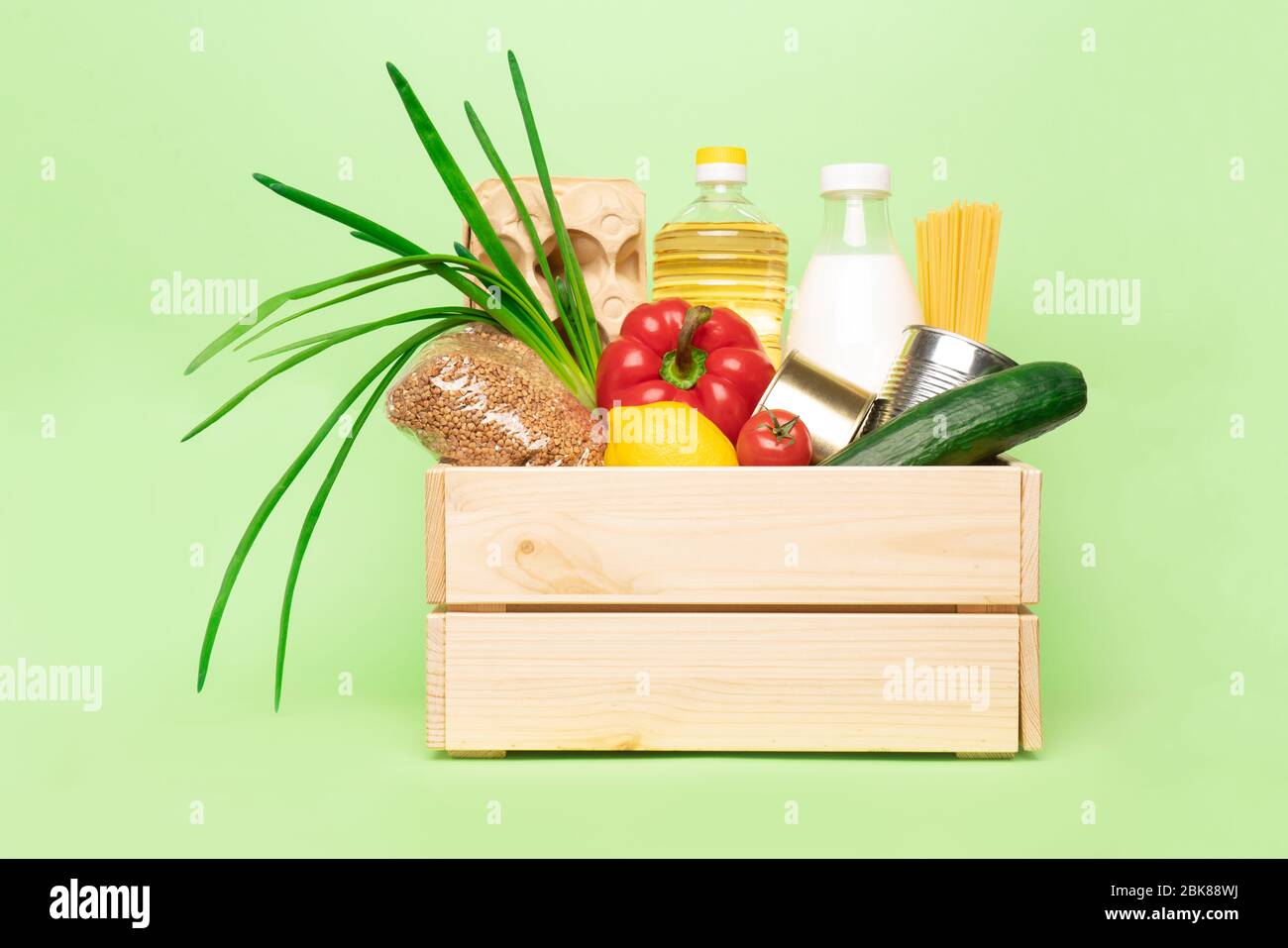 donation or delivery wooden box with food on green background. Stock Photo