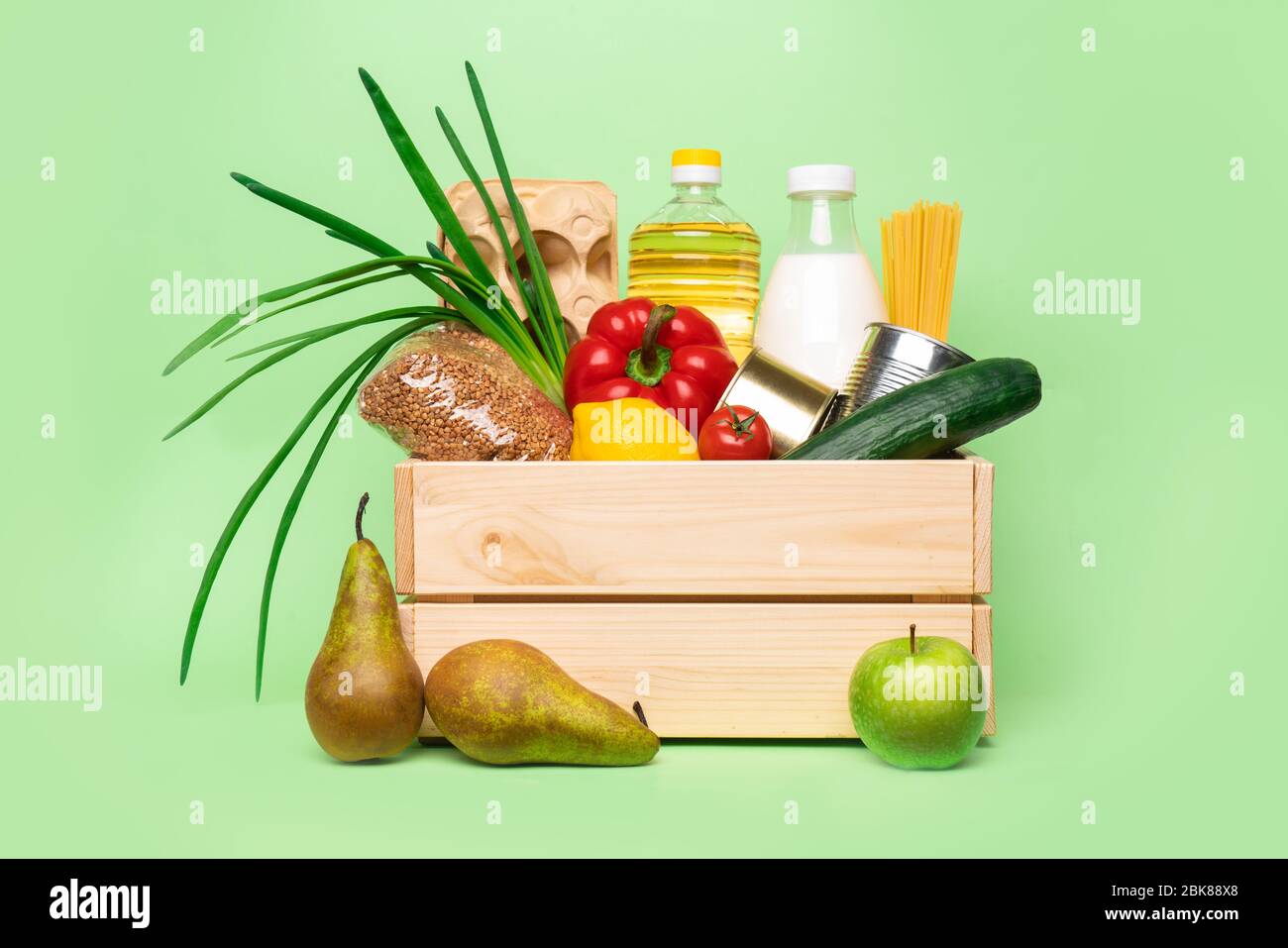 donation or delivery wooden box with food on green background. Stock Photo