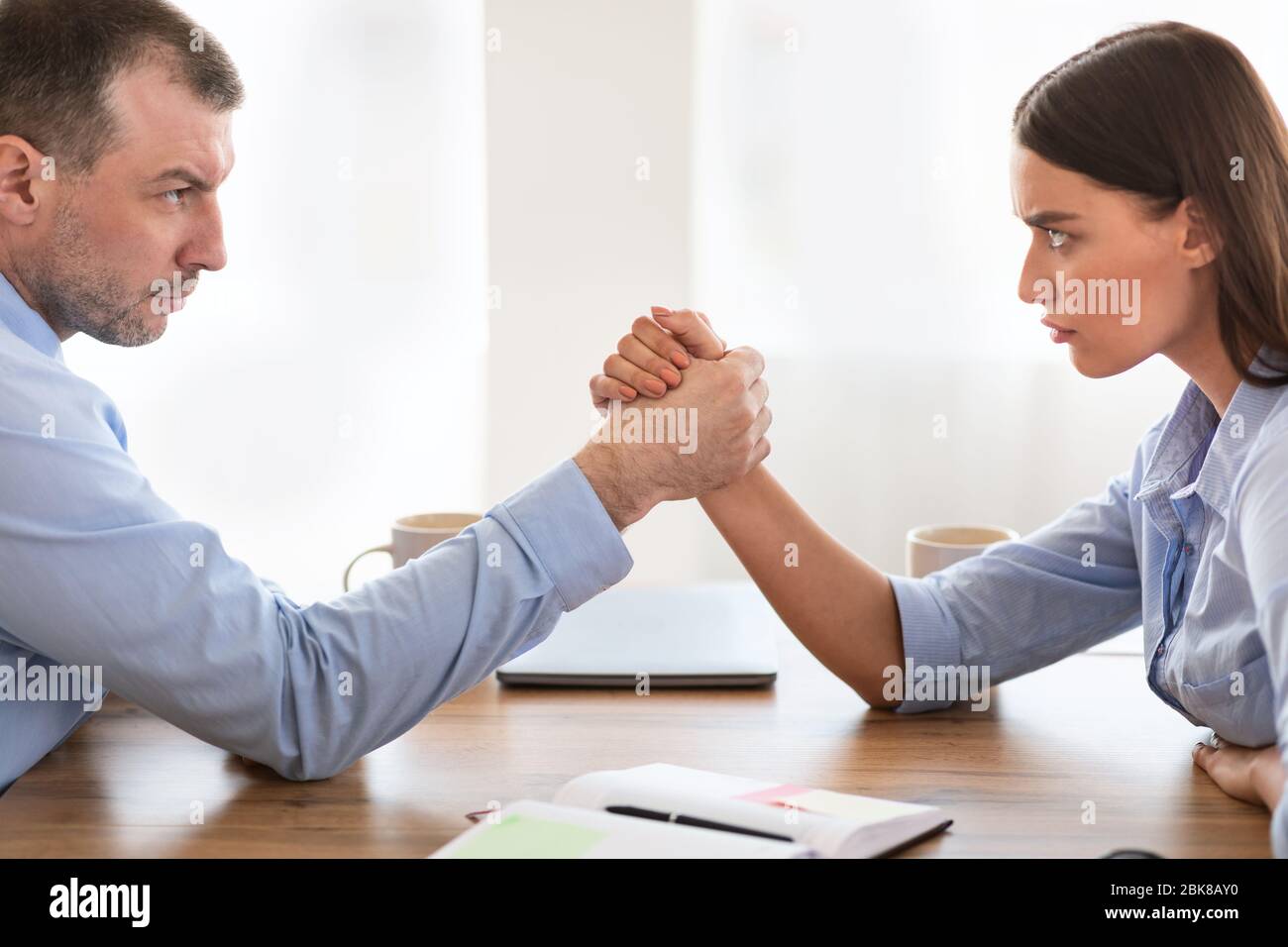 Businessman And Businesswoman Arm Wrestling Sitting At Desk In Office Stock Photo