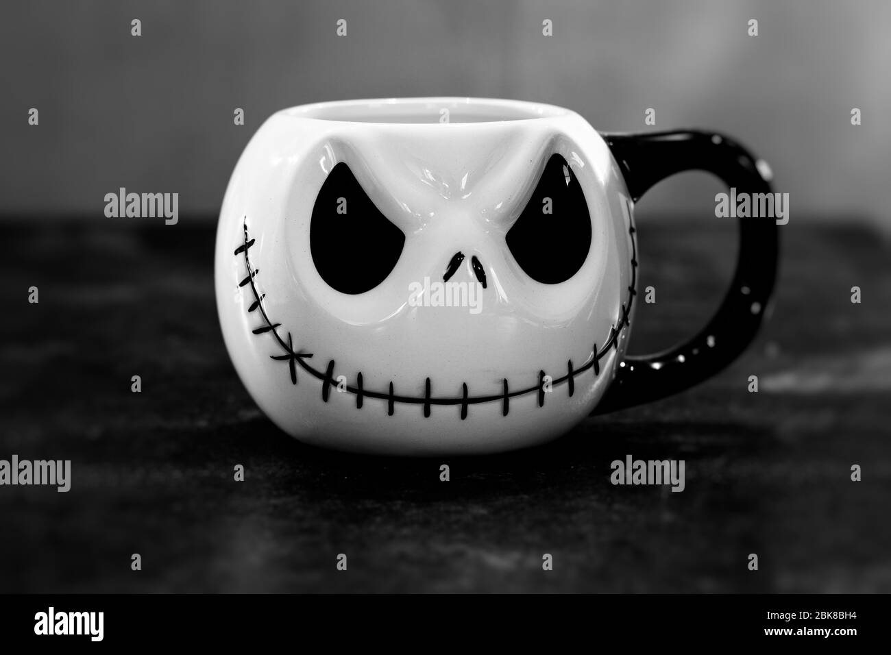 A Halloween face with a sewn-on mouth on a drinking cup, black and white Stock Photo