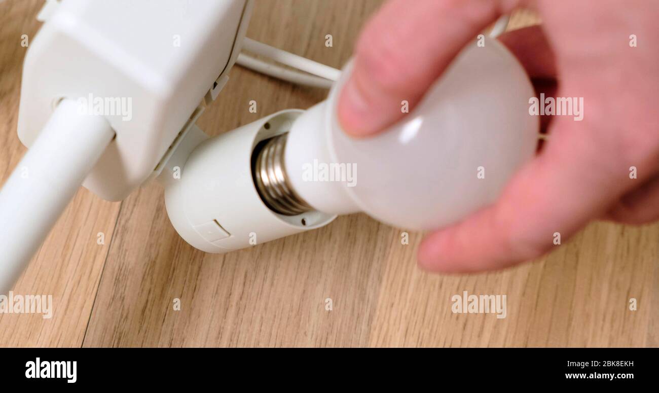 Mans Hands Replacing a Light Bulb in lamp. Close-Up. Stock Photo