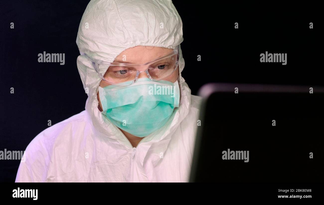 Portrait of masked laborant work on laptop. Stock Photo