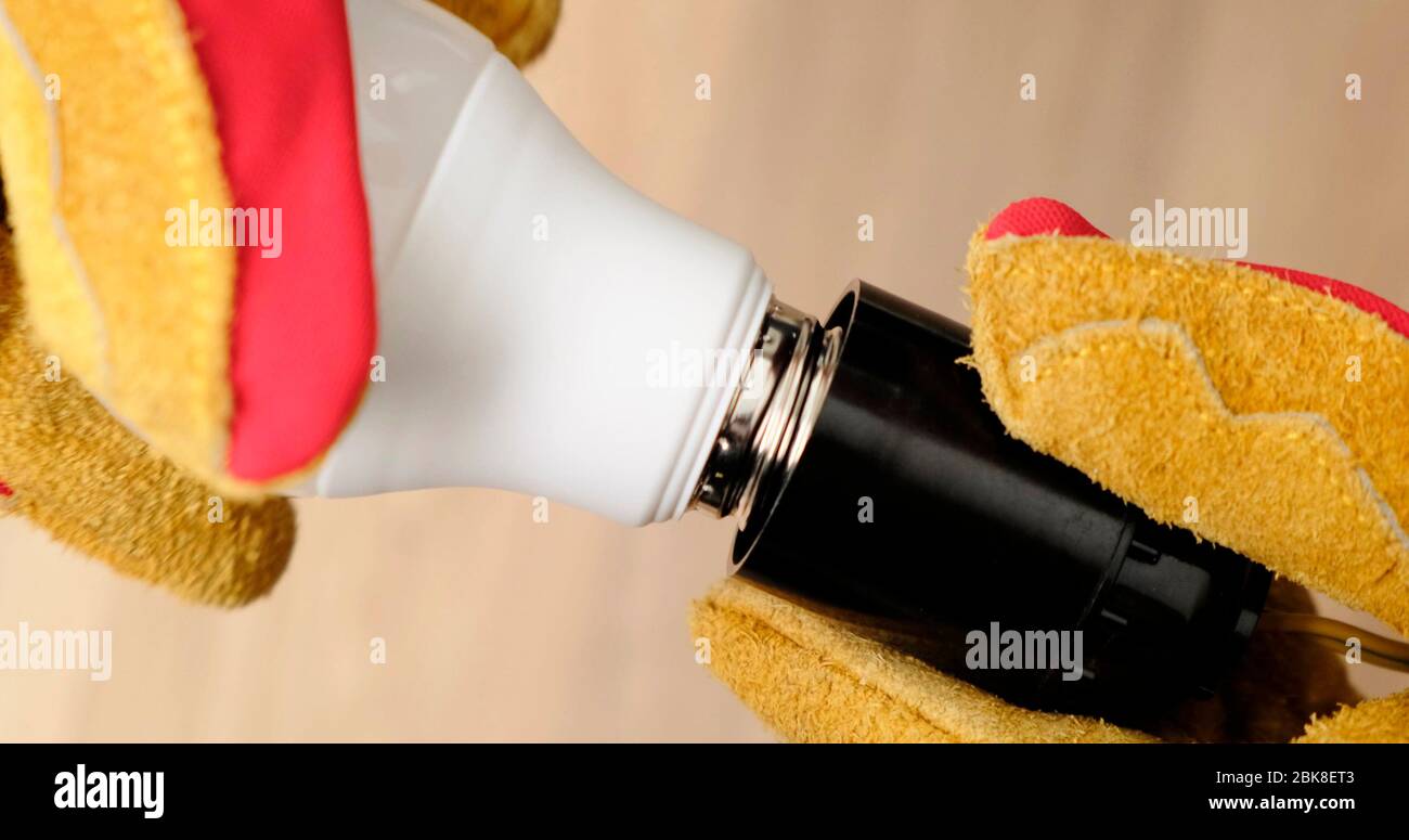Mans Hands Replacing a Light Bulb in lamp. Close-Up. Stock Photo
