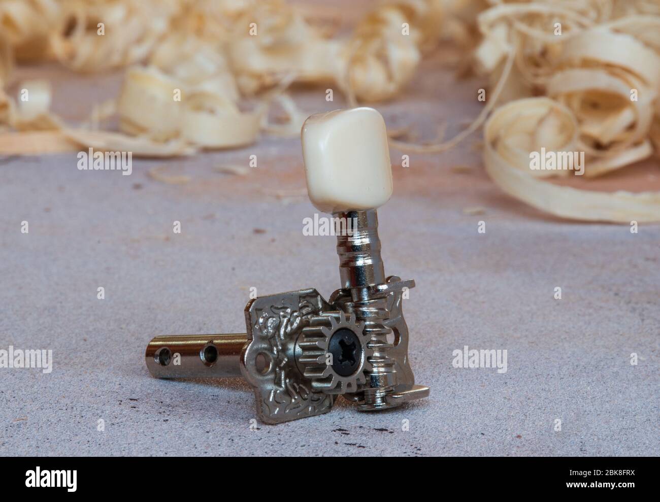 single tuning peg for classical guitar on the workbench with wood chips