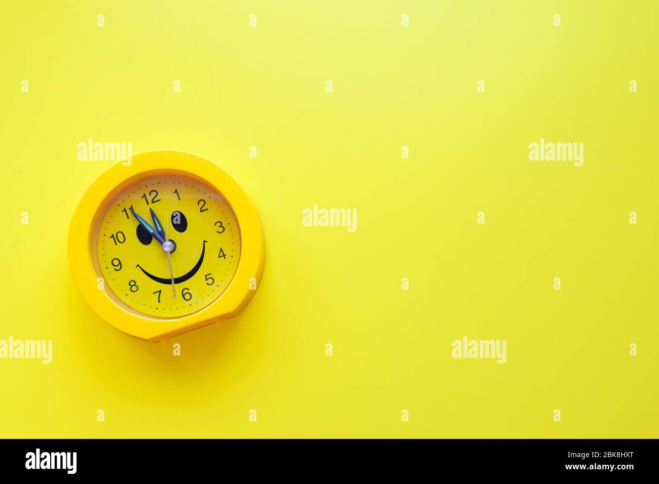 Yellow plastic smiling clock on yellow background. Good morning concept Stock Photo