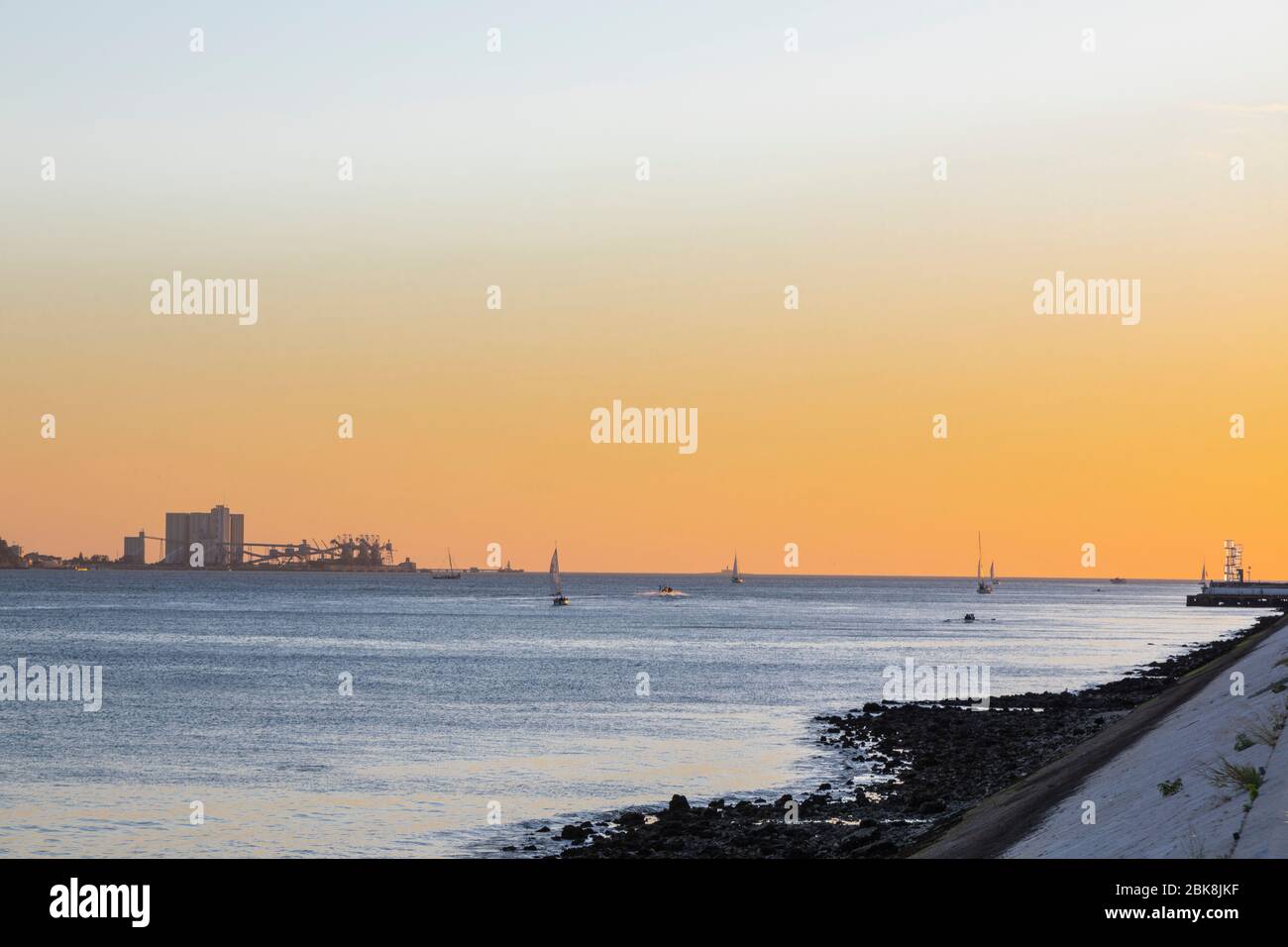 Sail boats on the Tagus river at sunset. Industry in the background, Lisbon, Portugal Stock Photo