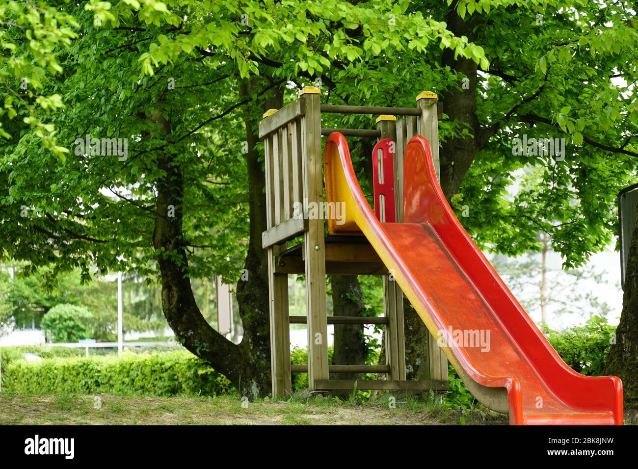 A red slide with a wooden ladder and construction in the park. The