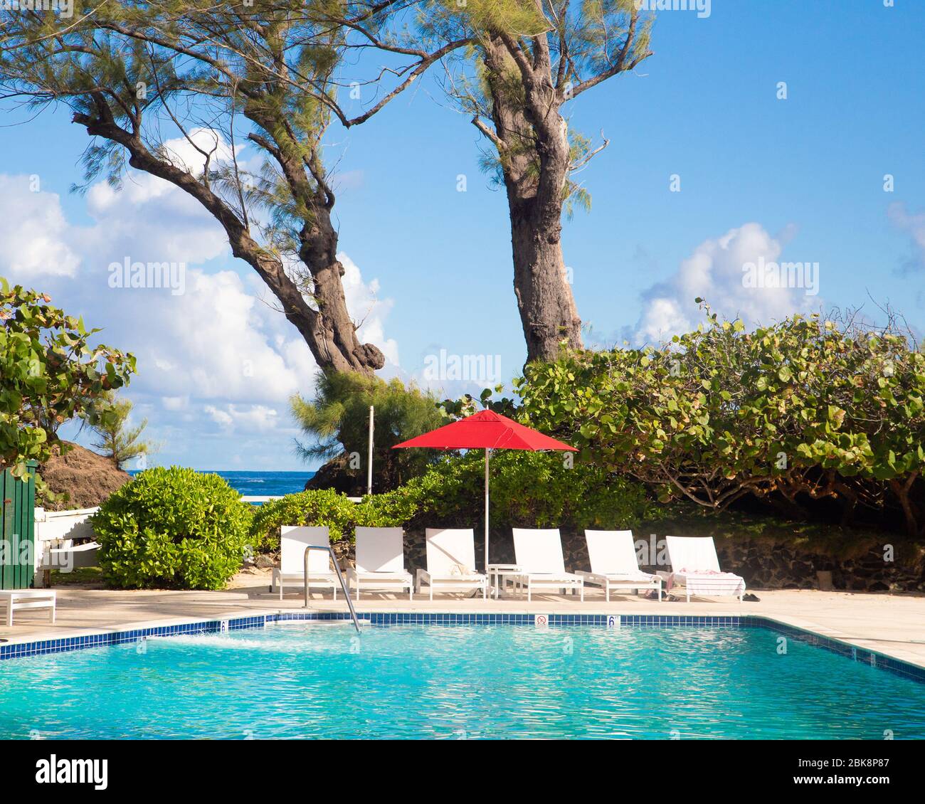 Lounge chairs and umbrella along swimming Pool Stock Photo