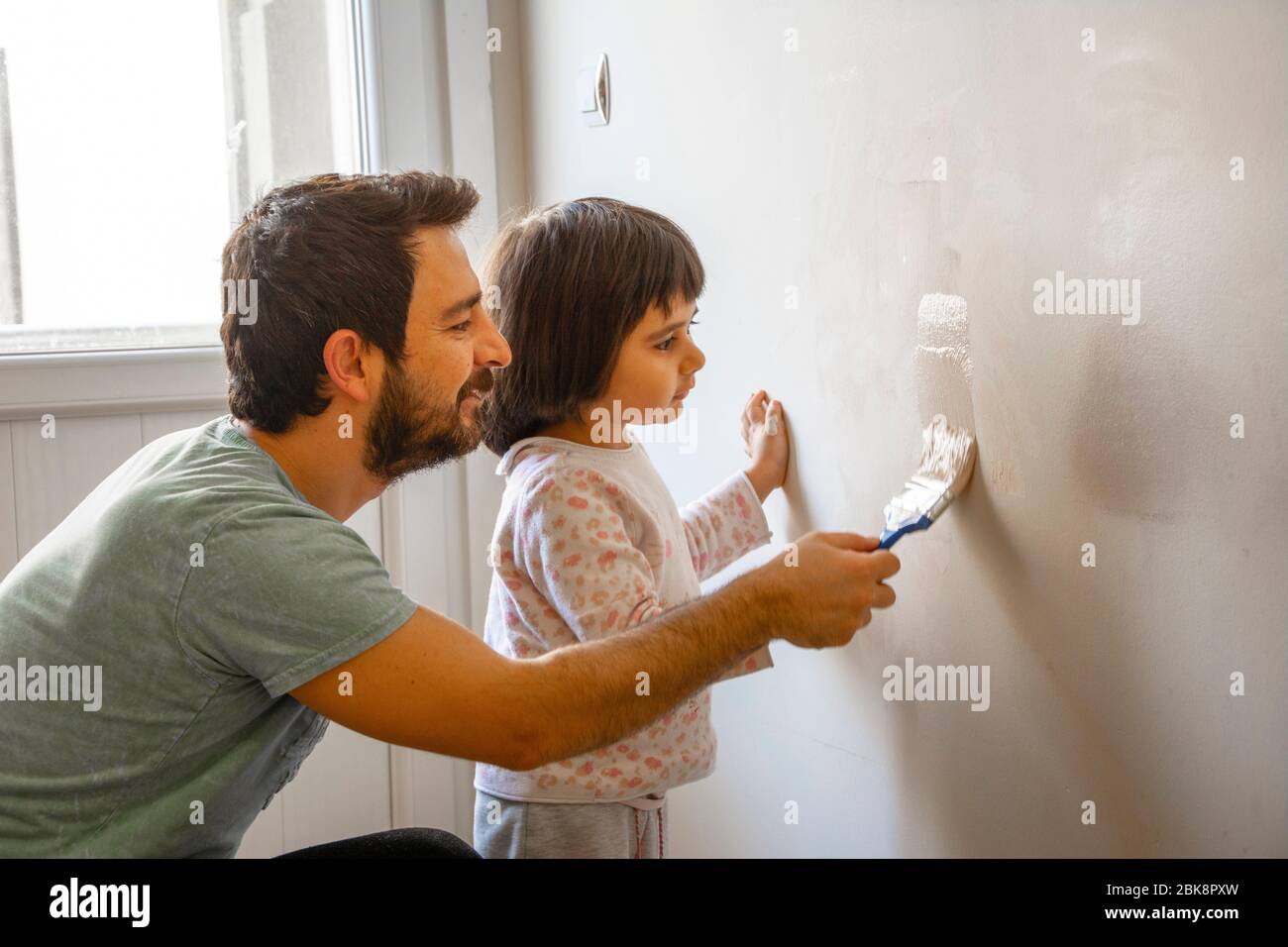 Father and her little daughter painting the wall Stock Photo