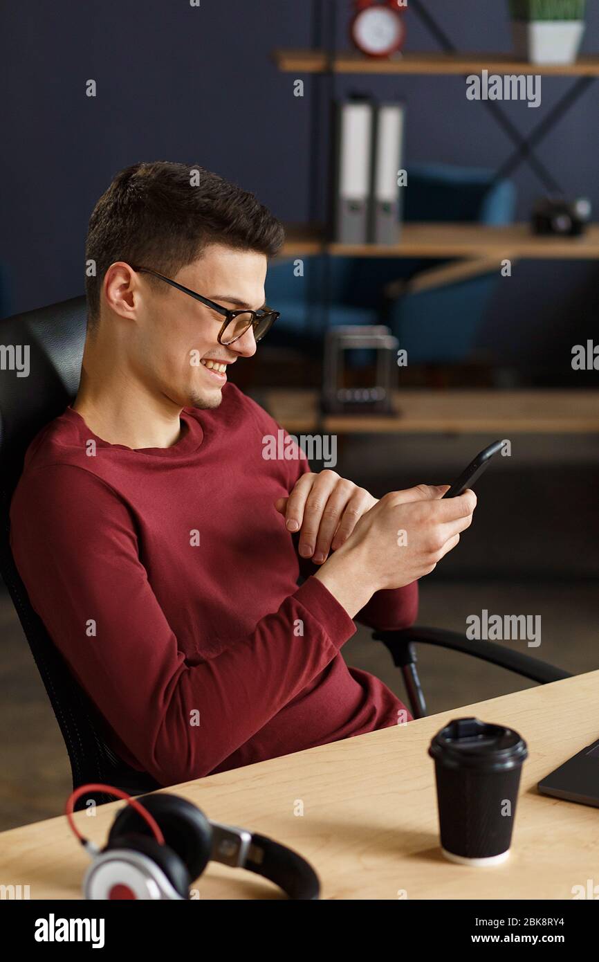 Young man using smartphone and smiling. Happy businessman using Stock Photo