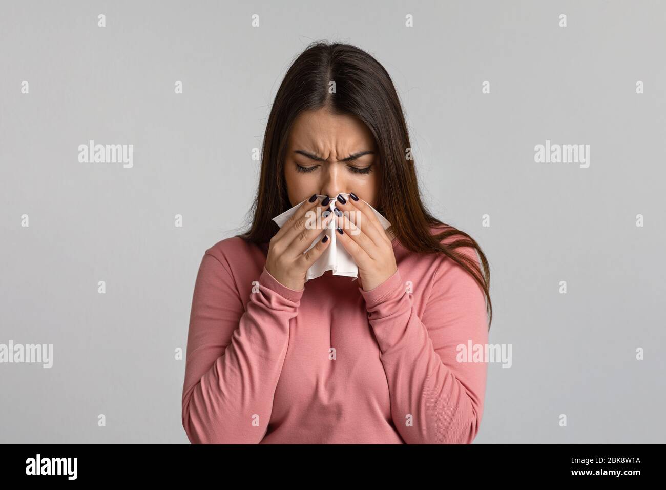 Coronavirus Symptoms. Sick woman sneezing and blowing nose into paper napkin Stock Photo