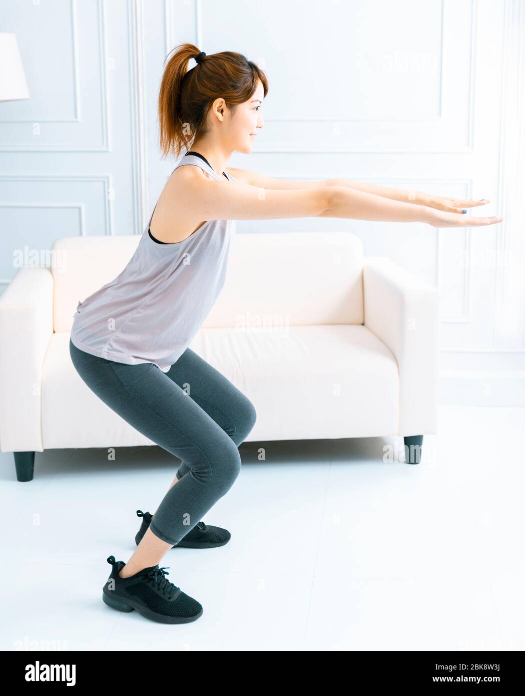 Young woman doing exercise at home in the living room Stock Photo