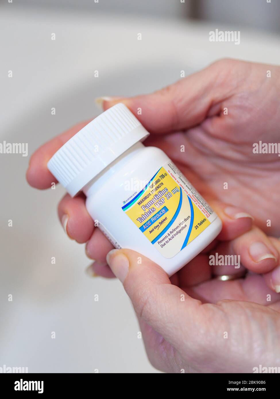 Woman's hands holding famotidine bottle 20 mg tablets. The drug is undergoing a trial as a treatment for COVID-19. Stock Photo