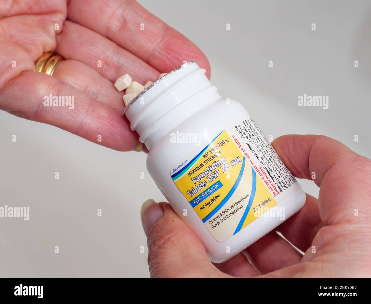 Woman's hands dispensing 20mg famotidine tablets from bottle. The drug is undergoing a trial as a treatment for COVID-19. Stock Photo