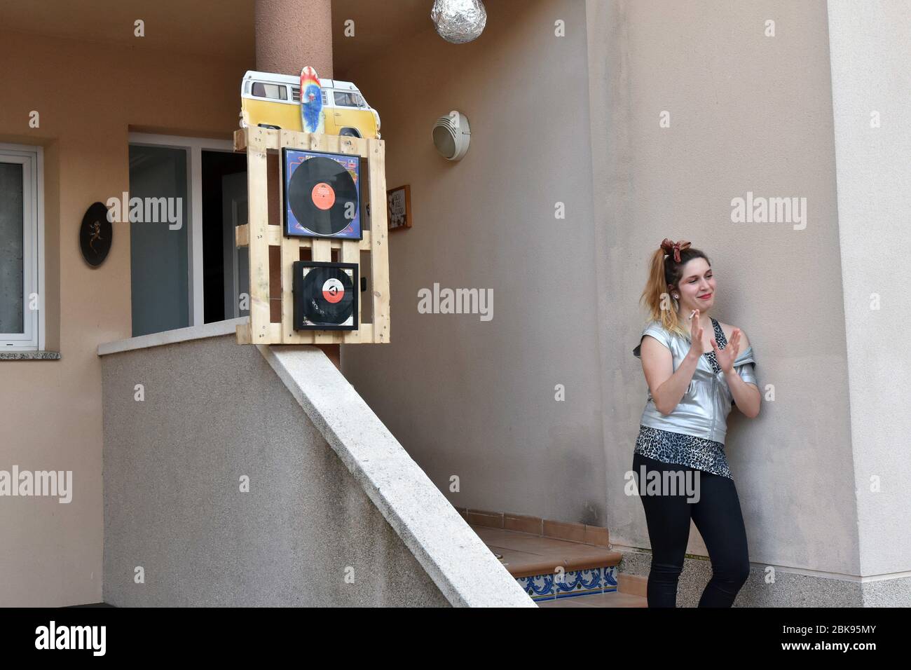 Vendrell, Spain. 25th Apr, 2020. A woman on the terrace of her house applauds during the 80s Music performance to encourage their neighbours during the confinement.Residents of the Mas d'en Gual neighbourhood perform and applause at 8 pm to cheer up their neighbours during the confinement amid the coronavirus crisis. This time they have chosen the theme of the Music of the 80s, a whole show where they were able to see pin up girls artists dressed as ABBA and a little Freddy Mercury. Credit: Ramon Costa/SOPA Images/ZUMA Wire/Alamy Live News Stock Photo