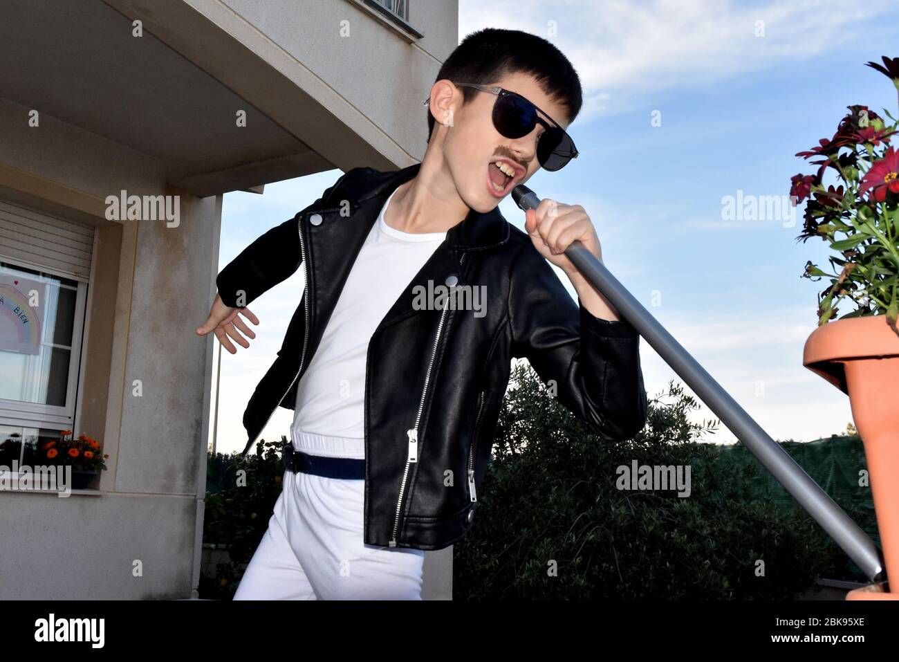 Vendrell, Spain. 25th Apr, 2020. A boy dressed as the singer of Queen Freddie Mercury seen during the 80s Music performance to encourage their neighbours during the confinement.Residents of the Mas d'en Gual neighbourhood perform and applause at 8 pm to cheer up their neighbours during the confinement amid the coronavirus crisis. This time they have chosen the theme of the Music of the 80s, a whole show where they were able to see pin up girls artists dressed as ABBA and a little Freddy Mercury. Credit: Ramon Costa/SOPA Images/ZUMA Wire/Alamy Live News Stock Photo