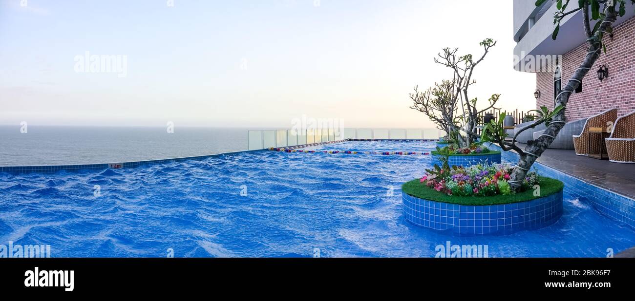 Swimming pool on the top of the building hotel resort with horizon skyline view in the morning Stock Photo