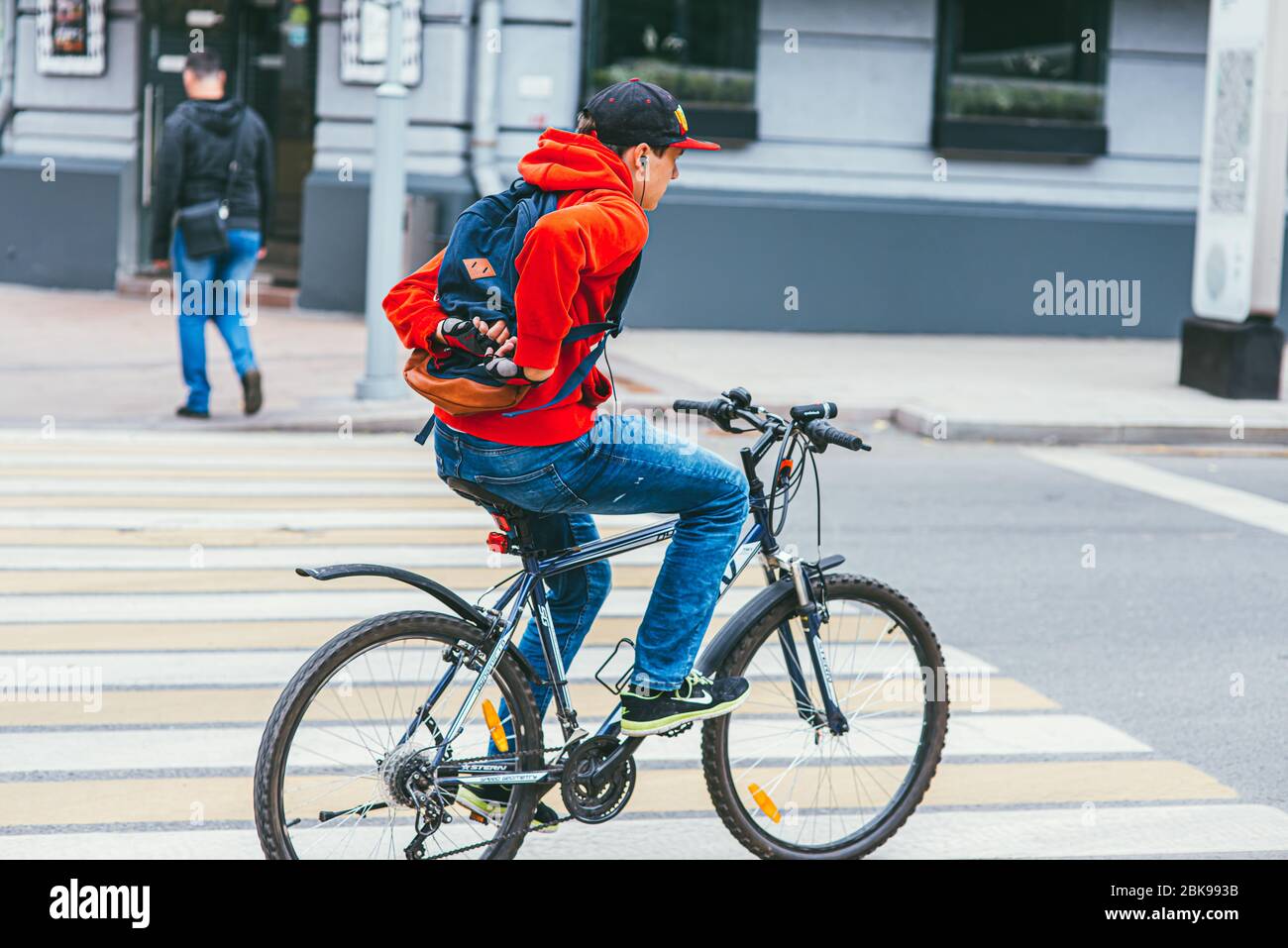 Moscow, Russia - JULY 7, 2017: A young man in a red hoodie crosses a pedestrian crossing on a Bicycle without hands Stock Photo