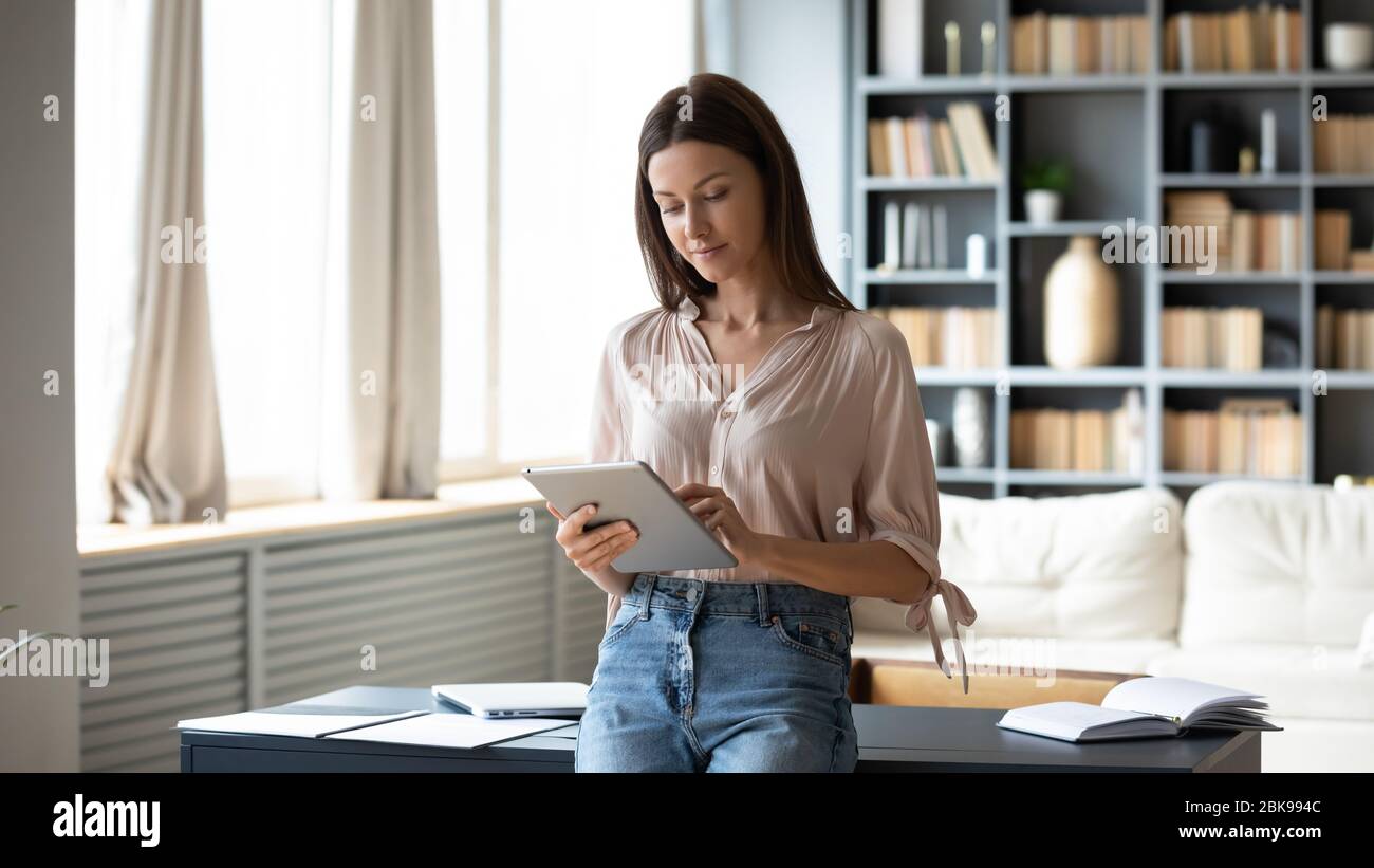 Beautiful young woman using computer tablet, standing at home Stock Photo
