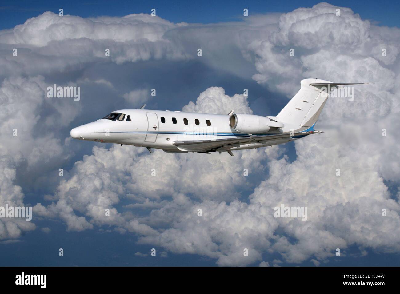 Private business jet airplane flying in the air at high altitude against a cloudy sky. Executive travel and flight. Stock Photo