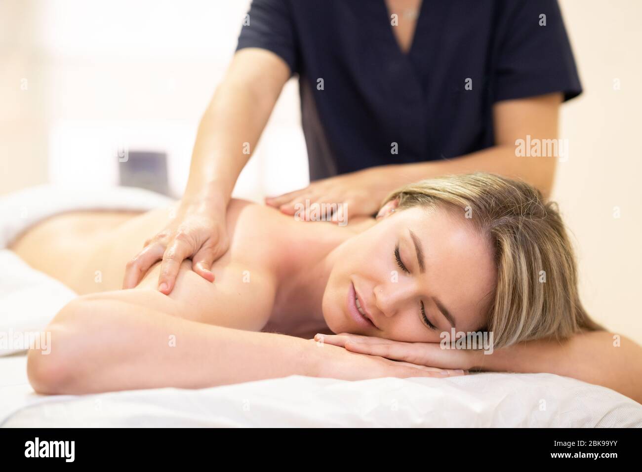Woman lying on a stretcher receiving a back massage. Stock Photo