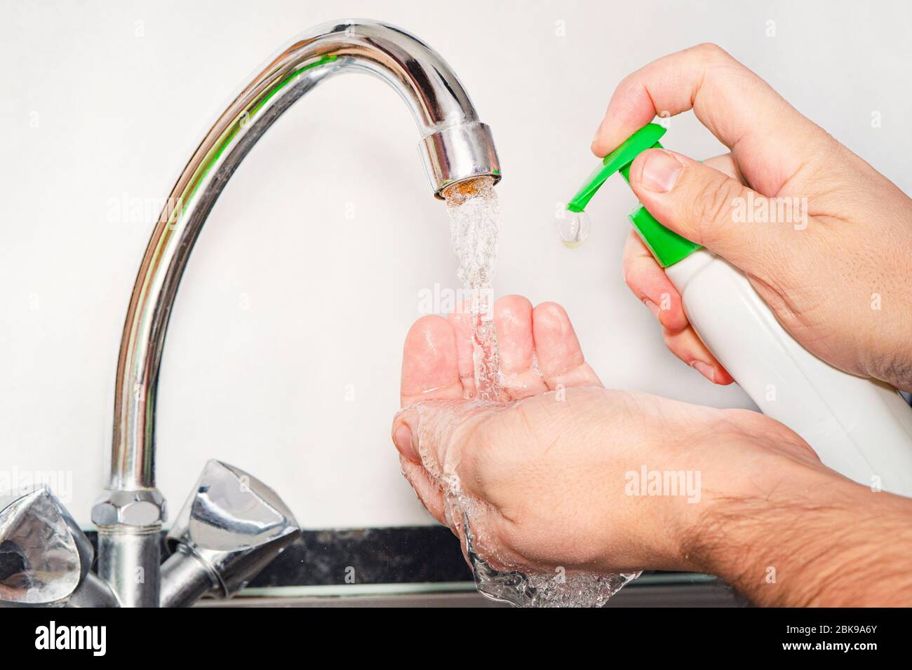 Man helping himself to a dollop of antibacterial soap, close up of hands. Washing hands rubbing with soap man for winter flu virus prevention, hygiene Stock Photo