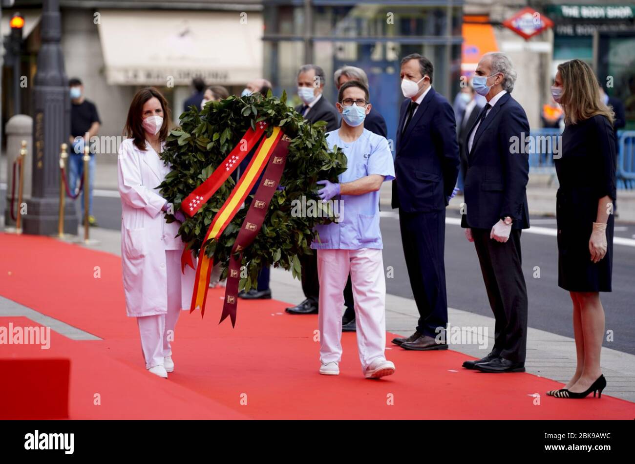(200503) -- MADRID, May 3, 2020 (Xinhua) -- Two health workers carry a flower wreath during a moment of silence observed for COVID-19 victims at the Puerta del Sol square in Madrid, Spain, May 2, 2020. (Madrid Region Government/Handout via Xinhua) Stock Photo