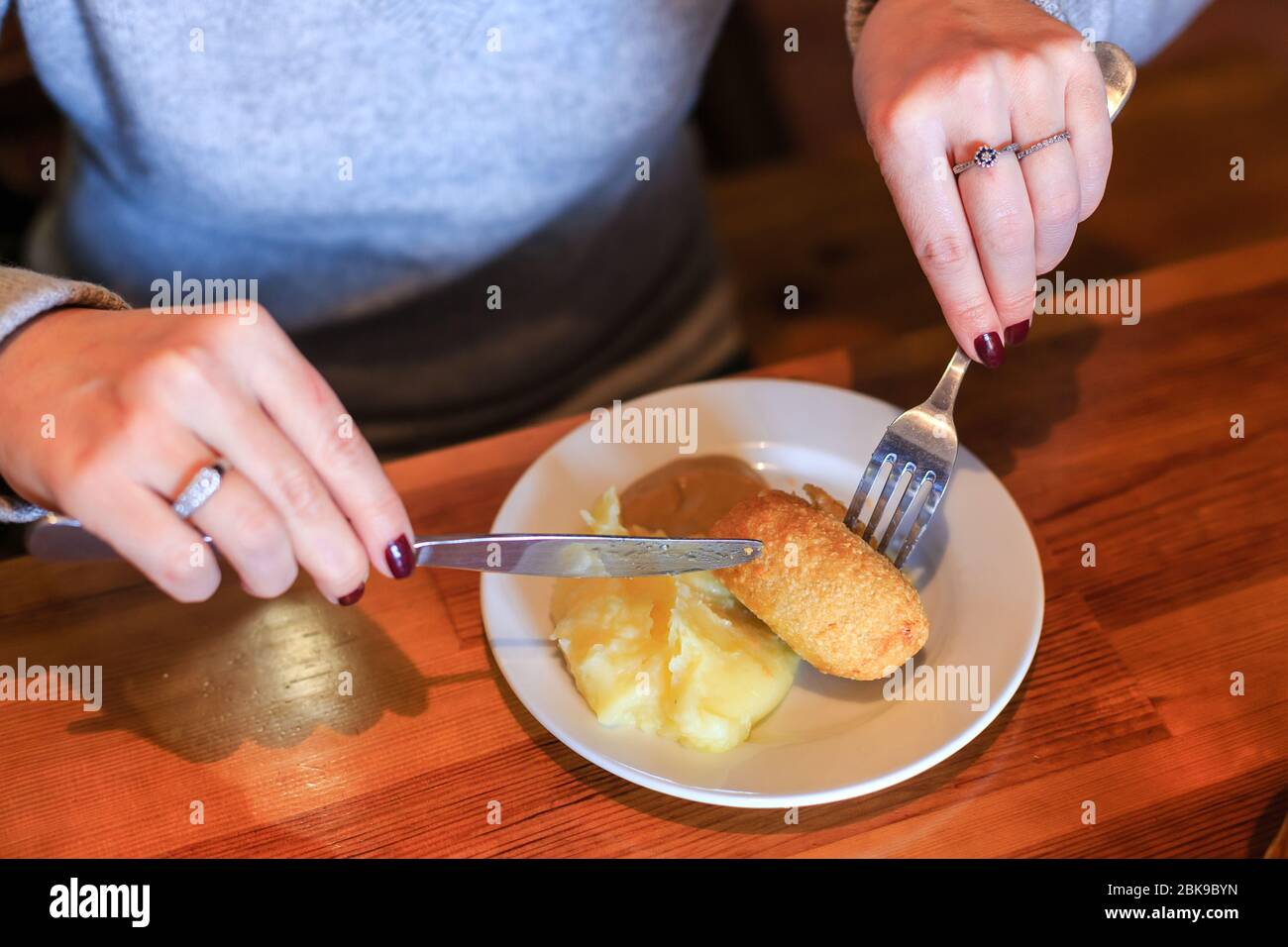 Woman uses a knife and fork for eating a cutlet Stock Photo Alamy