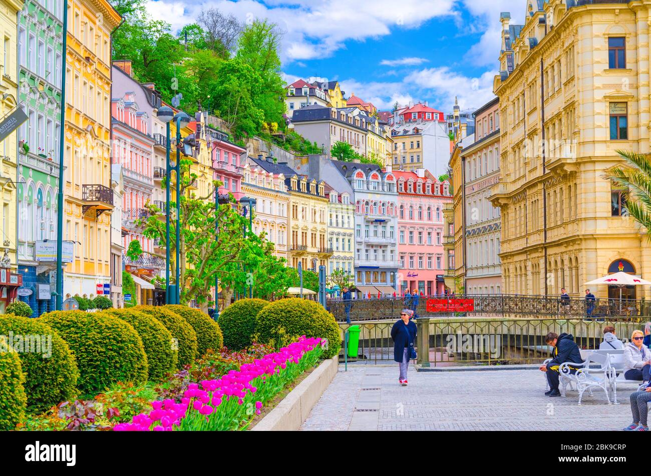 Karlovy Vary, Czech Republic, May 9, 2019: people are walking down street and Tepla river embankment in Carlsbad historical city centre with colorful traditional beautiful buildings, West Bohemia Stock Photo