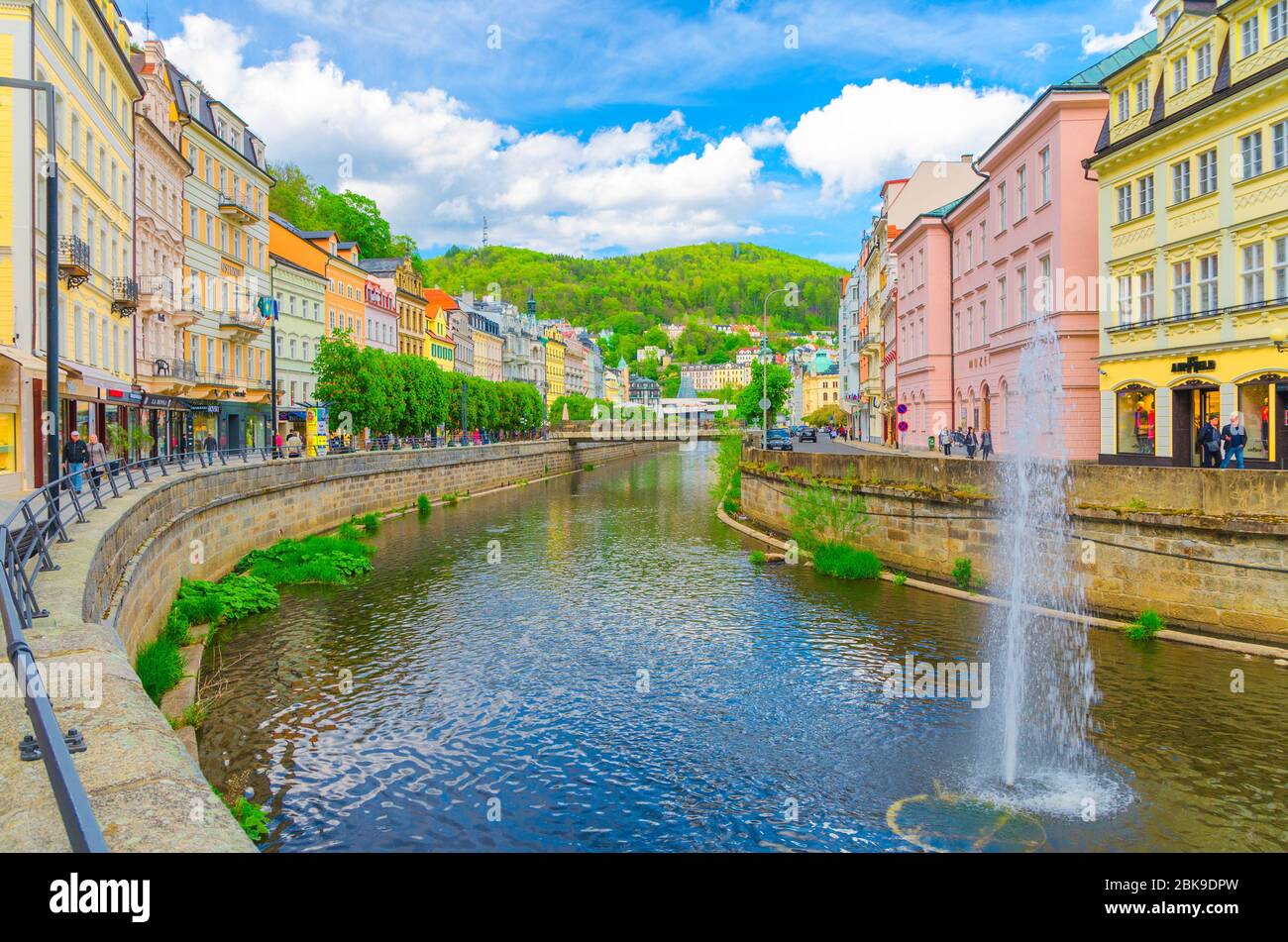Karlovy Vary, Czech Republic, May 10, 2019: people are walking down street and Tepla river embankment in Carlsbad historical city centre with colorful traditional beautiful buildings, West Bohemia Stock Photo