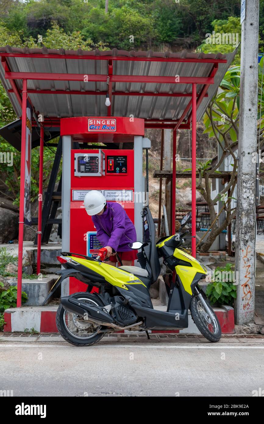 Koh Tao, Thailand, February, 2020: Young thai woman fills fuel in her scooter at self service station Stock Photo