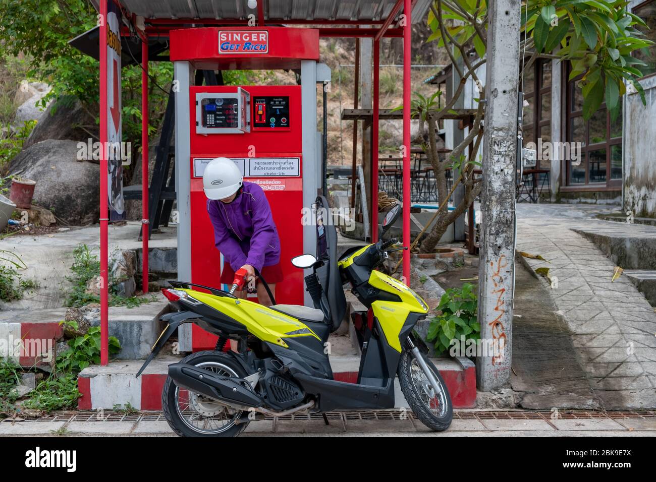 Koh Tao, Thailand, February, 2020: Young thai woman fills fuel in her scooter at self service station Stock Photo