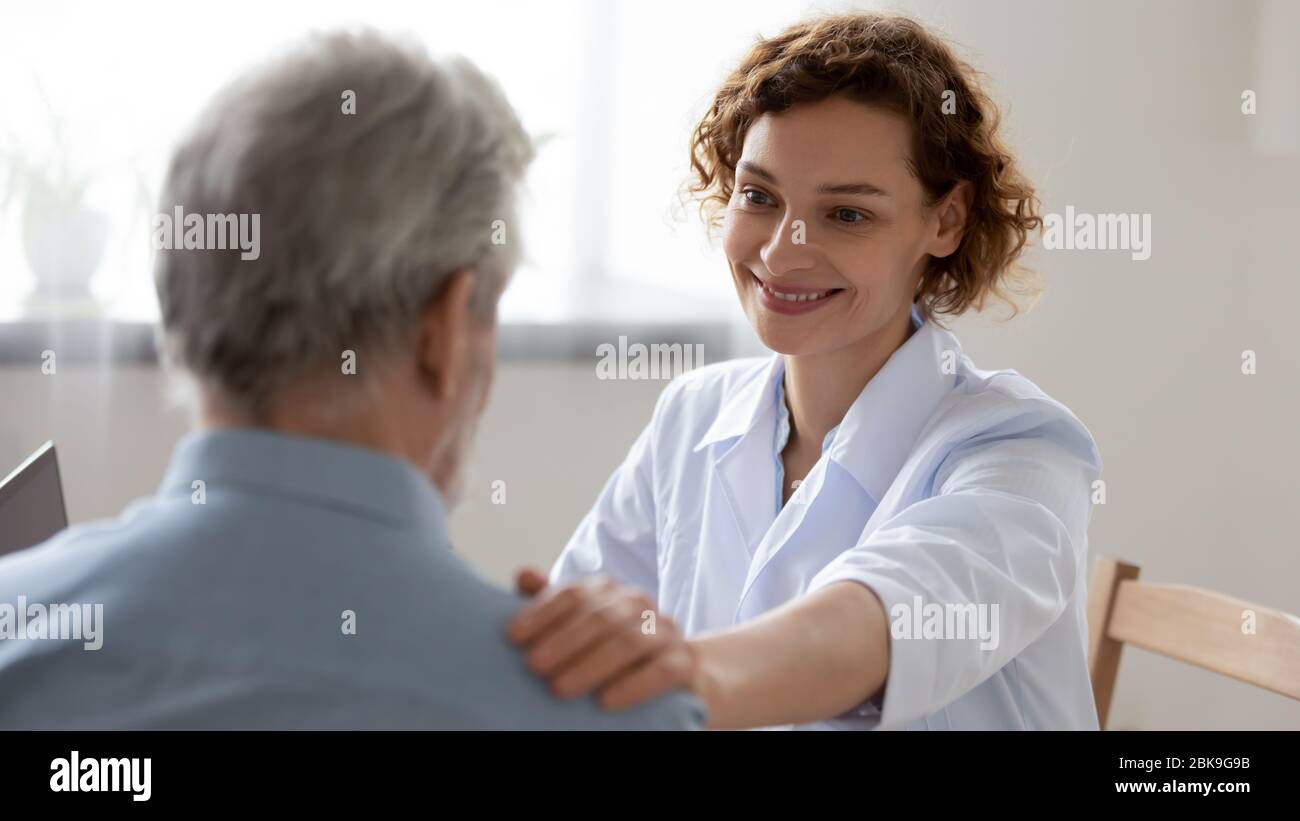 Smiling female doctor reassuring supporting senior patient in hospital Stock Photo