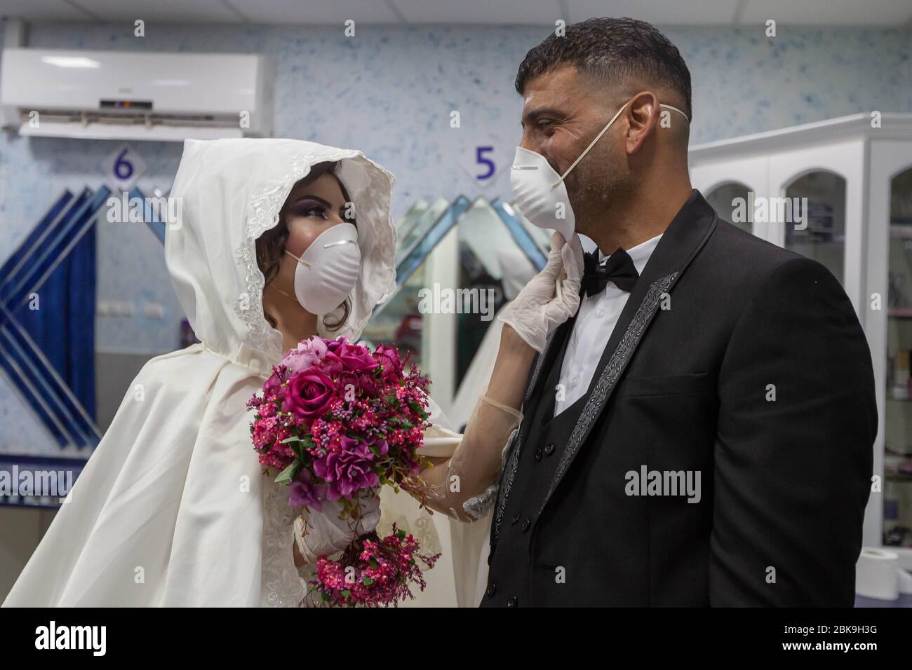 Beijing, Palestinian Deheisheh refugee camp near the West Bank city of Bethlehem. 10th Apr, 2020. Palestinian bride Shima' al-Titi adjusts the face mask for her groom, Ishaq Musleh, before they leave the beauty salon in the Palestinian Deheisheh refugee camp near the West Bank city of Bethlehem, April 10, 2020. Credit: Luay Sababa/Xinhua/Alamy Live News Stock Photo